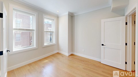 A room with a white door and two windows with blinds.