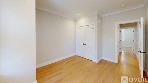 A room with wooden floors and white walls, with a door on the right side.