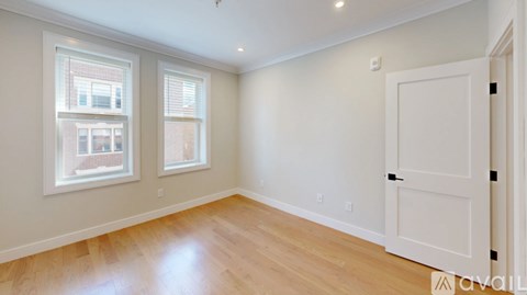 A room with a white door and two windows with white frames.