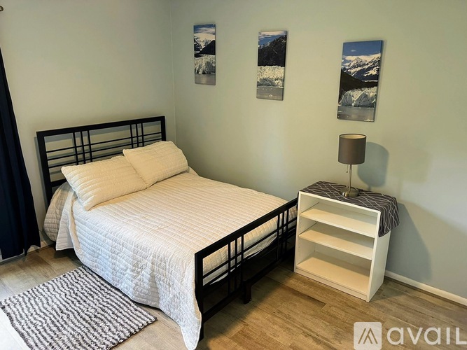 A bedroom with a bed, nightstand, and pictures on the wall.