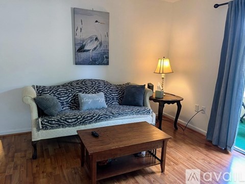 A living room with a couch, a table, and a painting on the wall.