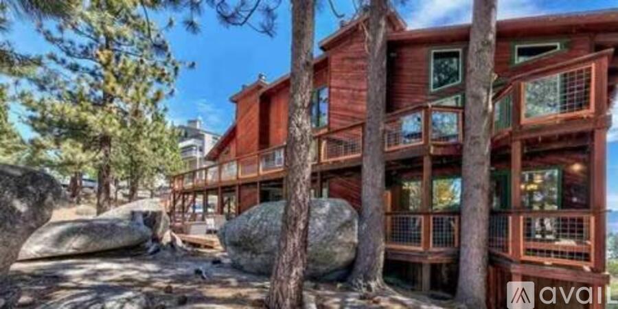 A wooden cabin with a balcony surrounded by trees.