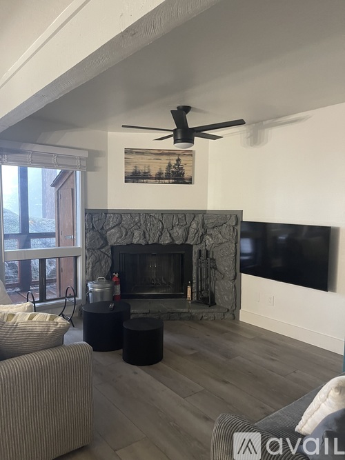 A living room with a stone fireplace and a flat screen TV mounted above it.
