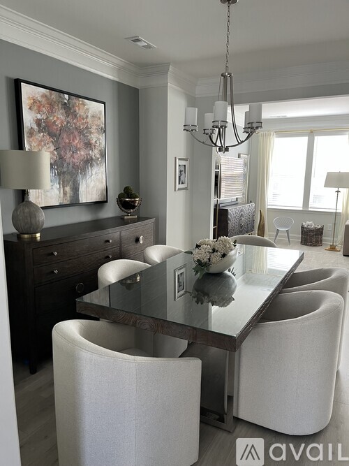 A modern dining room with a glass table and white chairs.