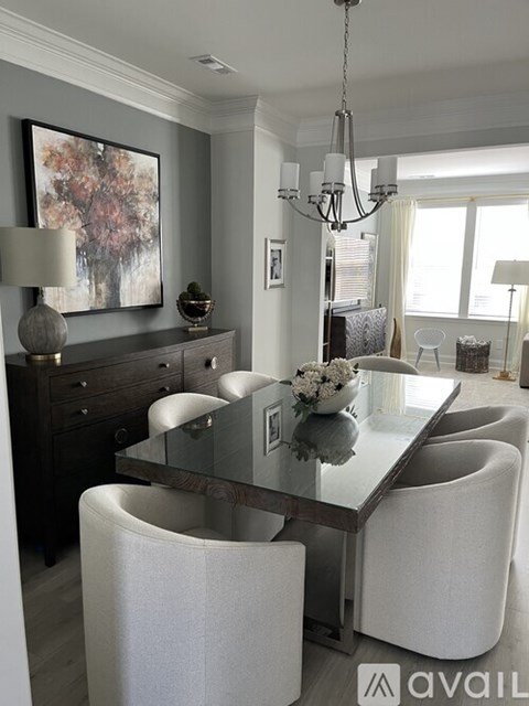 A modern dining room with a glass table and white chairs.