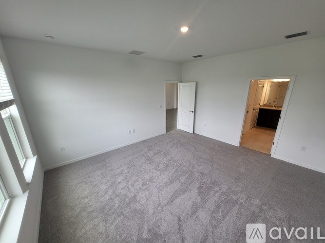 A spacious room with a grey carpet and white walls.
