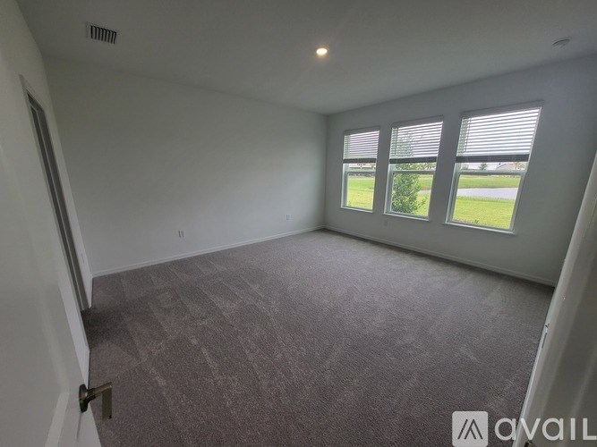 A room with a carpeted floor and a window with blinds.
