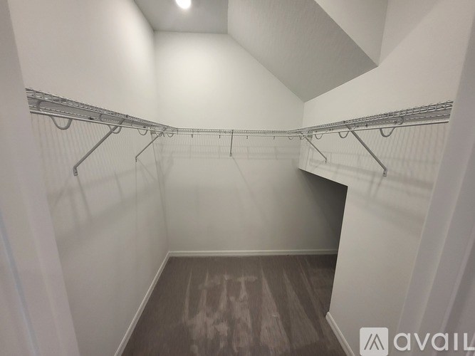 A walk-in closet with white walls and wooden floors.