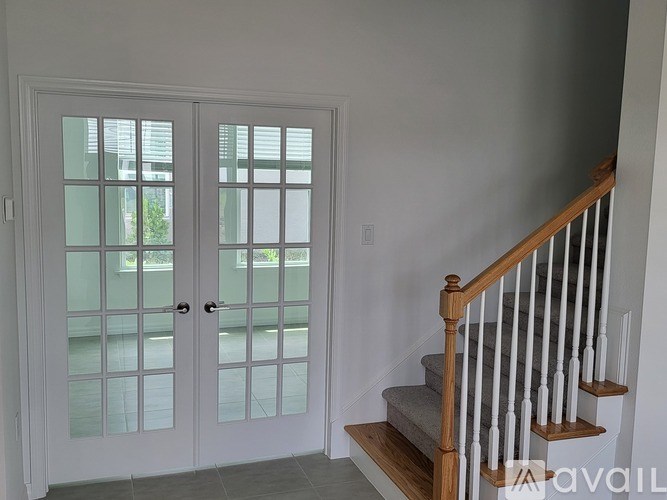 A white door with a glass panel and a wooden staircase with white railings.