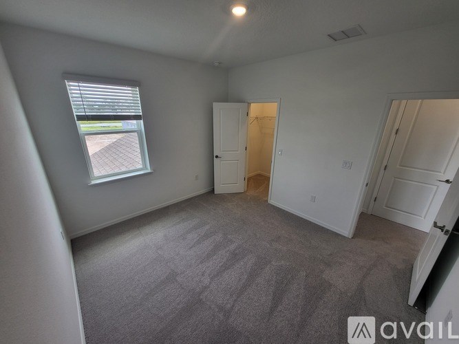 A room with a grey carpet and a window with blinds.