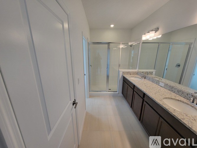 A bathroom with a walk-in shower and double sinks.