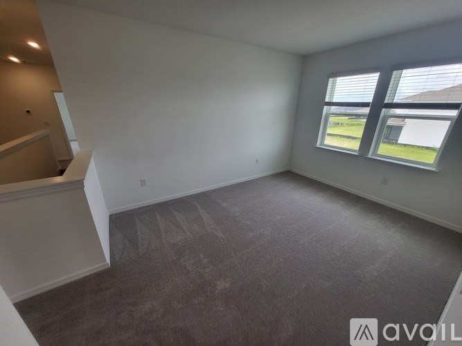 A spacious room with a carpeted floor and a window with blinds.