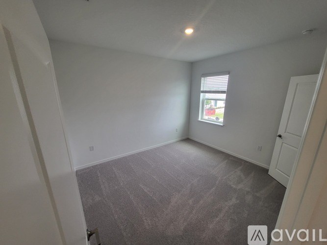 A room with a carpeted floor and a window with blinds.