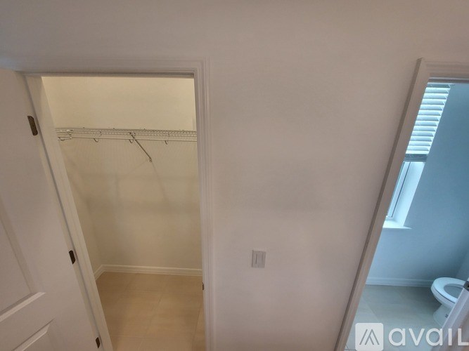 A small white closet with a towel rack and a toilet in the background.