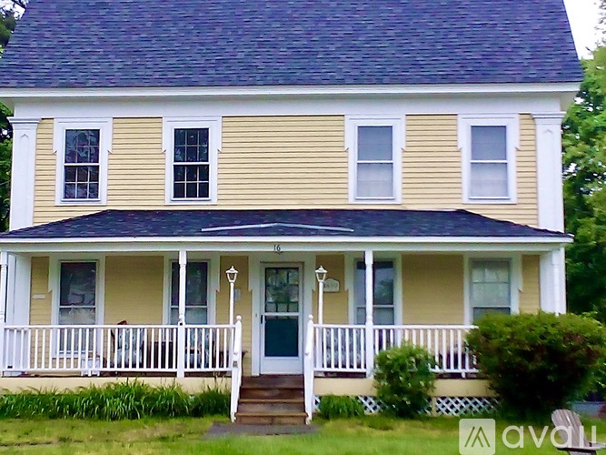 A yellow house with a white porch and a green door.