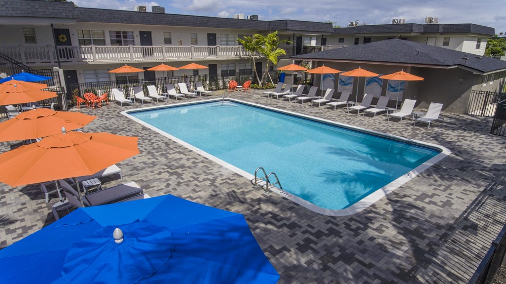 A pool surrounded by orange and blue umbrellas.