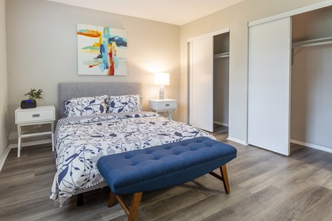 A bedroom with a large bed and a blue ottoman.