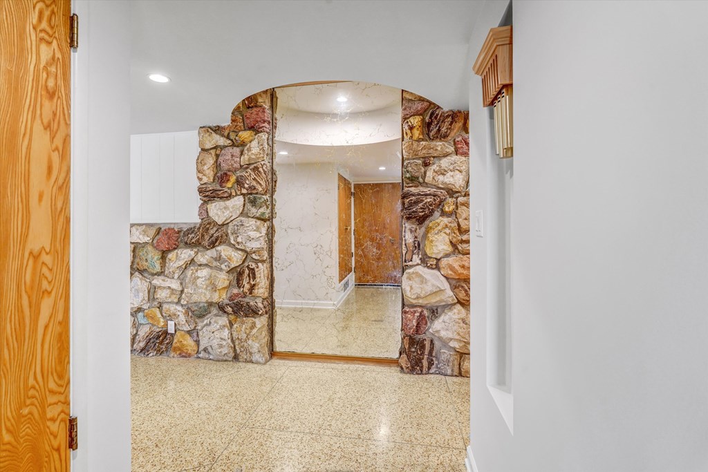 A hallway with a stone wall and a wooden door.