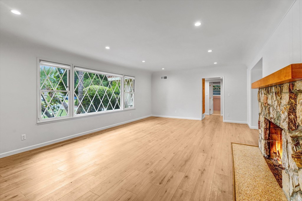 A room with a fireplace and a window with a view of trees.