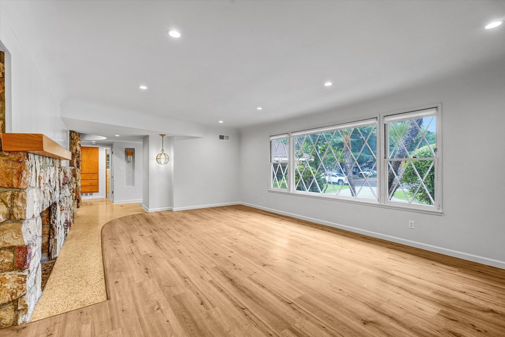 A spacious room with wooden floors and a stone wall.
