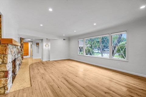 A spacious room with wooden floors and a stone wall.