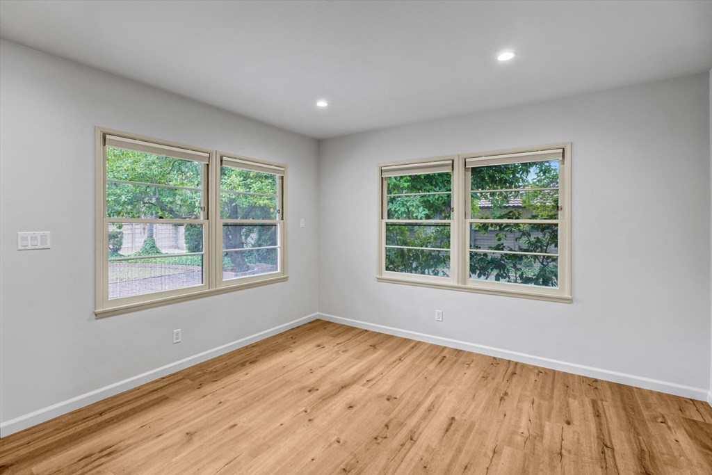A room with two windows and wooden flooring.