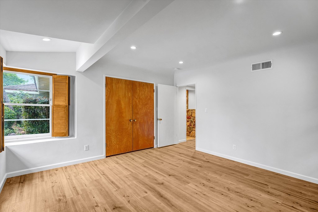 A room with a wooden floor and a window with blinds.