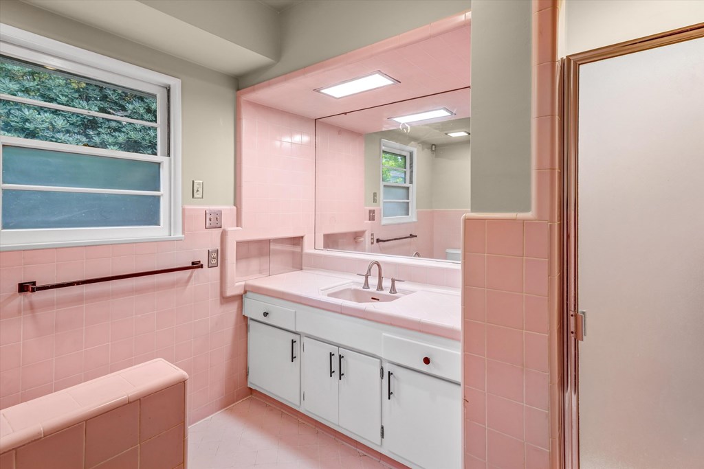 A bathroom with pink walls and white fixtures.