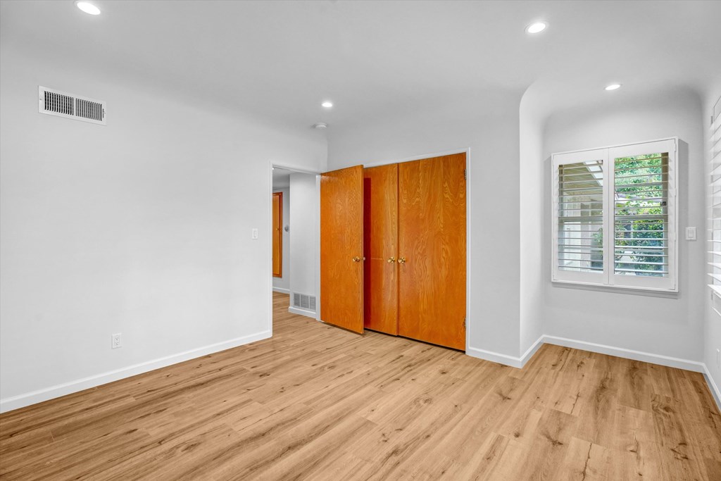 A room with wooden floors and a window with blinds.