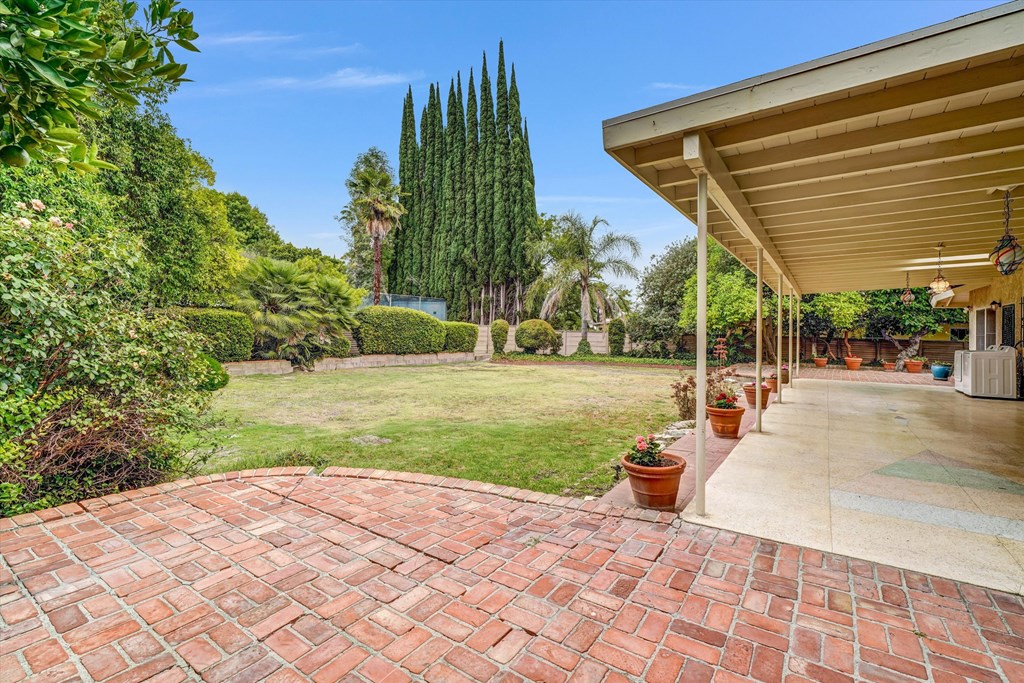 A patio with a brick walkway leads to a covered area.