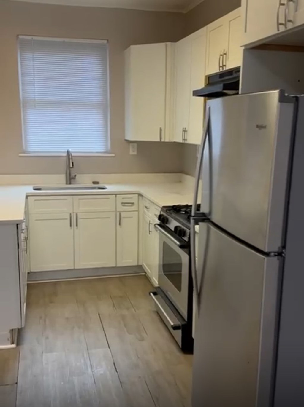 A kitchen with a refrigerator, oven, and cabinets.