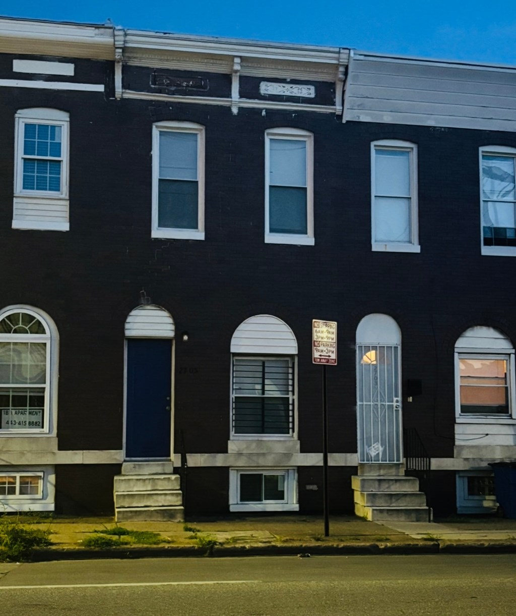A black building with white trim and a blue door.
