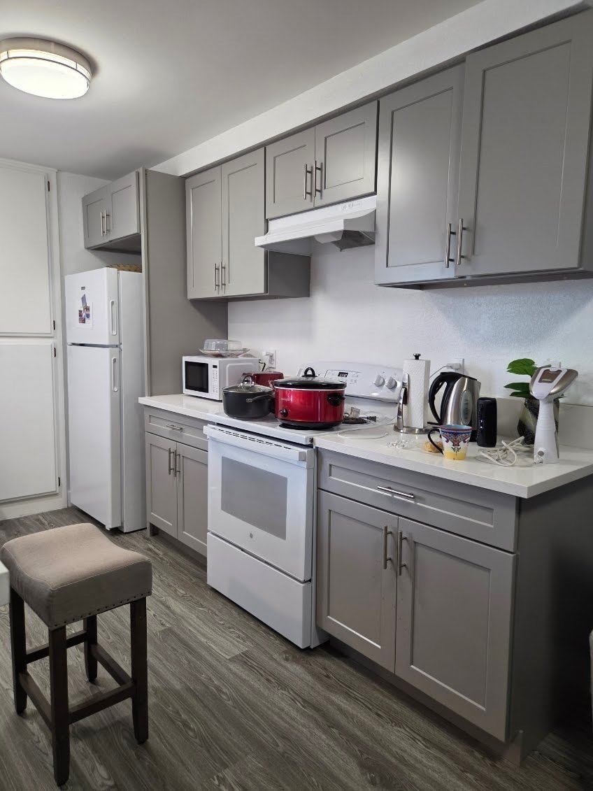 A kitchen with a white fridge, white oven, and a grey counter.