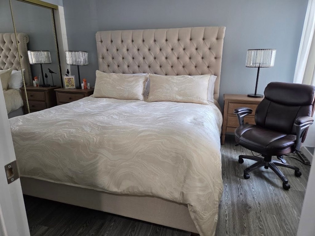 A bedroom with a large bed and a chair.