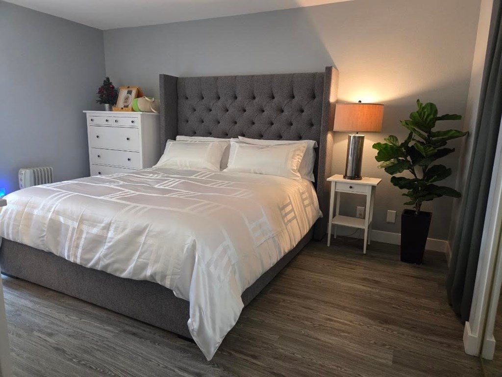 A bedroom with a large bed and a grey headboard.