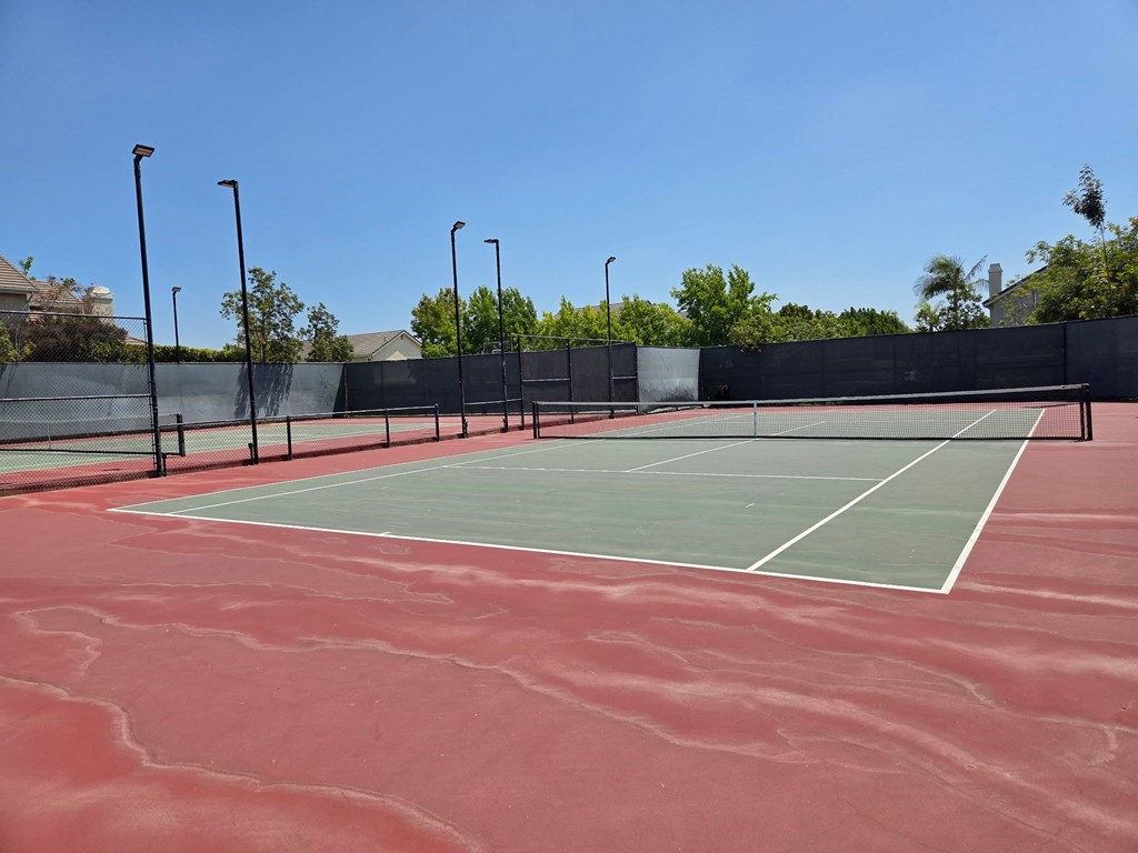 A tennis court with a red surface and white lines.
