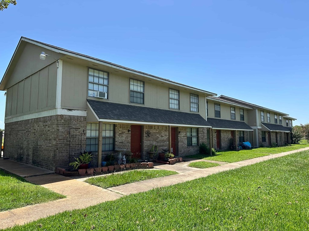A row of houses with a blue car parked in the driveway of the second house from the left.