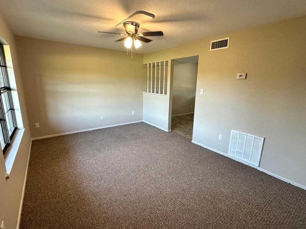 A room with a ceiling fan and carpeted floor.