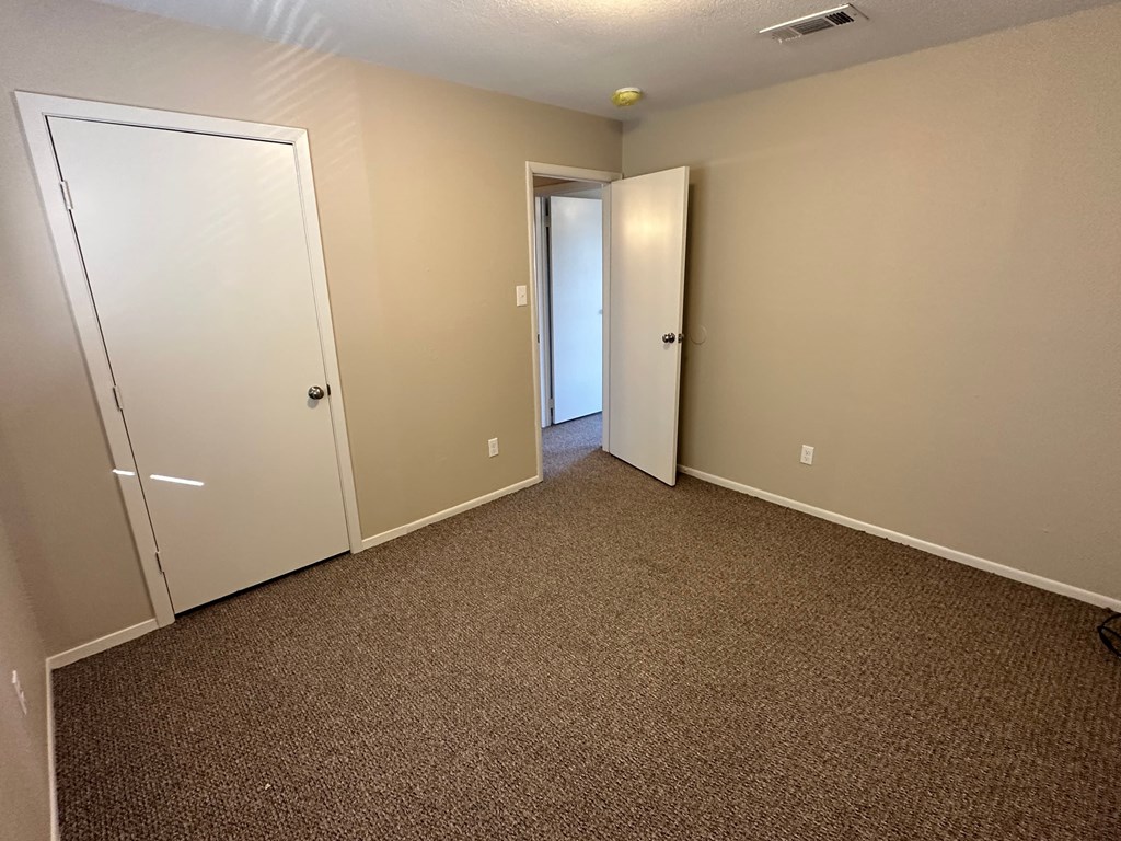 A carpeted room with two doors, one of which is open.