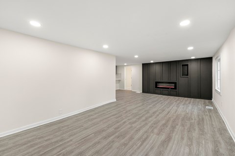 A spacious room with a fireplace and wood flooring.