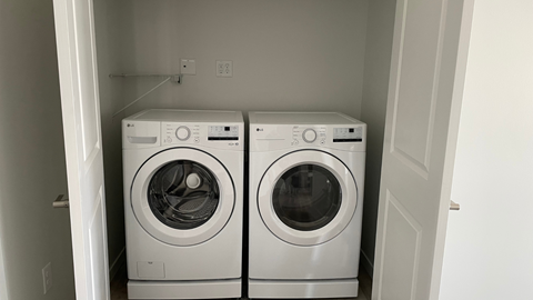 Two white front loading washing machines in a small laundry room.