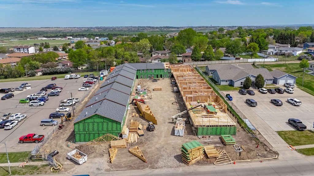 A construction site with a green building and a long wooden structure under construction.