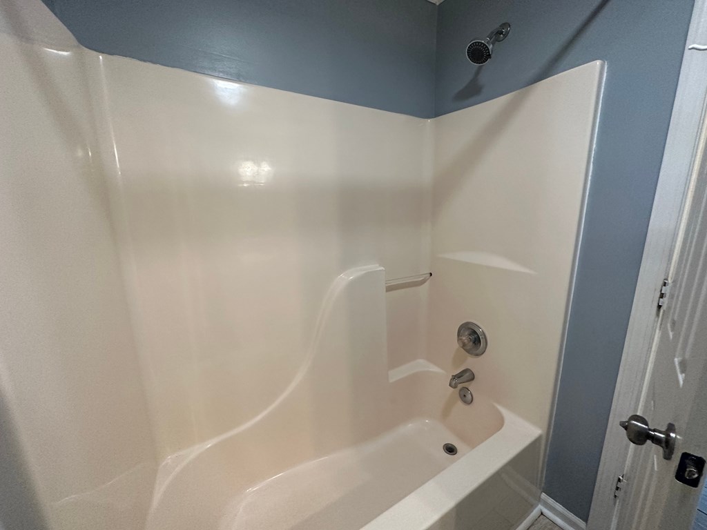 A white bathtub with a shower head and faucet.