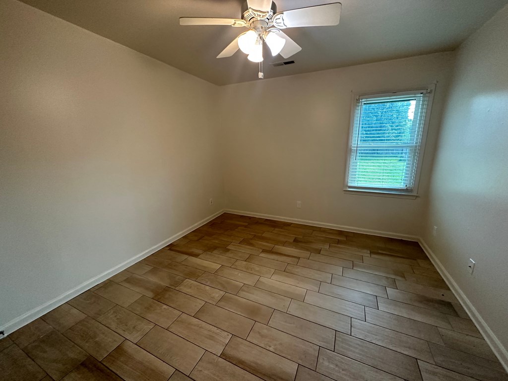 A room with a ceiling fan and a window with blinds.