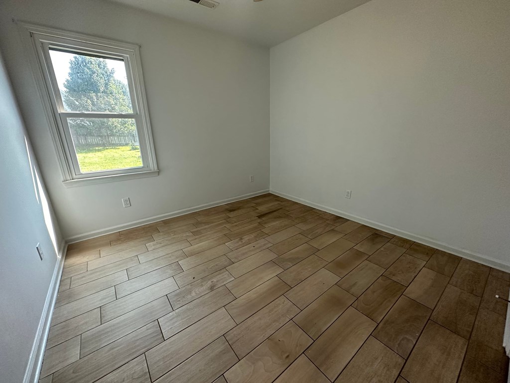 A room with a window and wooden flooring.