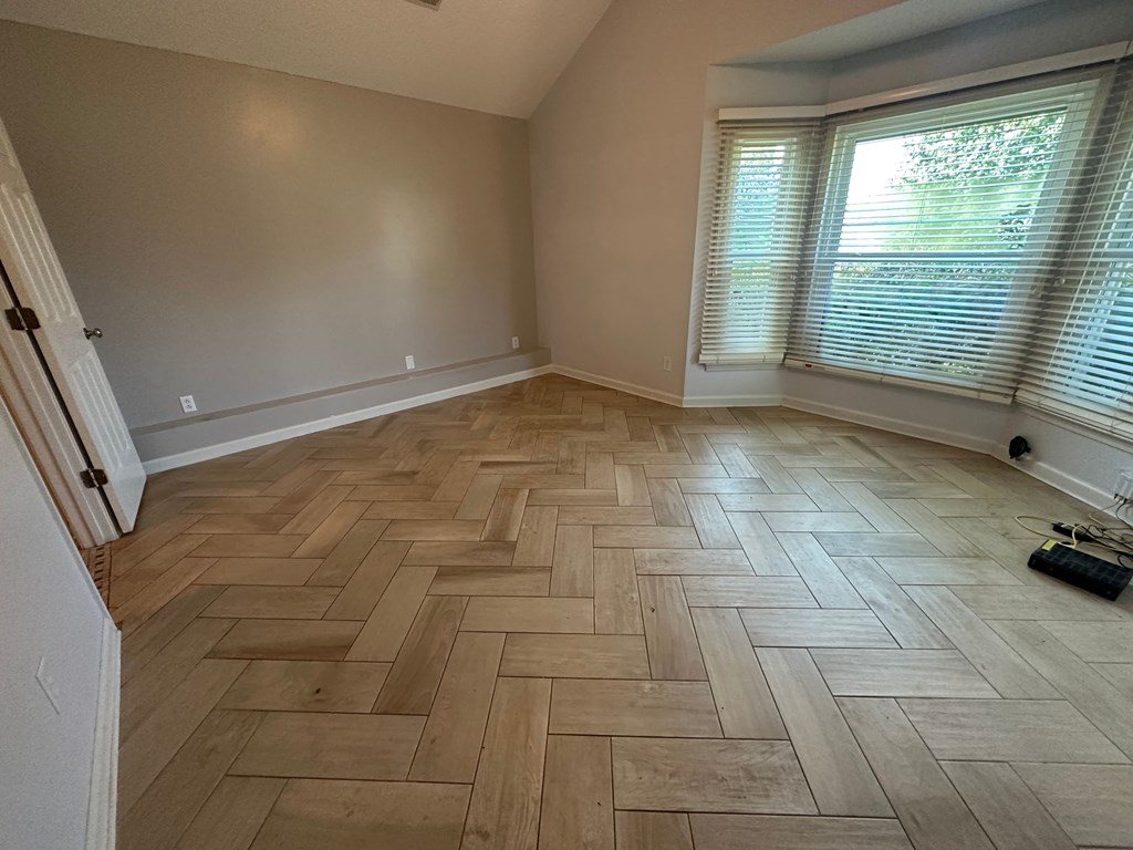 A room with wooden flooring and a window with blinds.