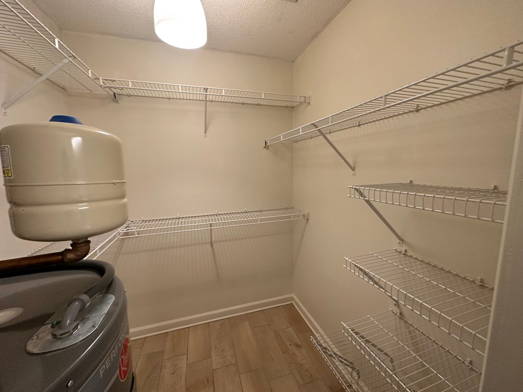 A small, empty walk-in closet with a white door and a white ceiling.