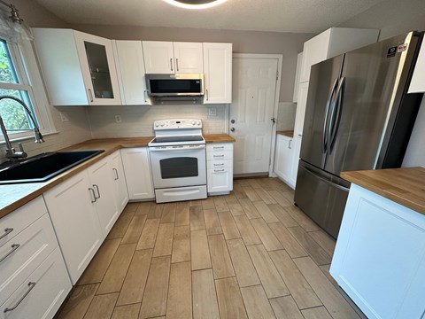A kitchen with white cabinets and a wooden counter.