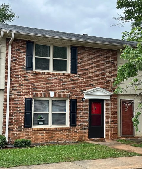 A red brick house with a black door and a red door.