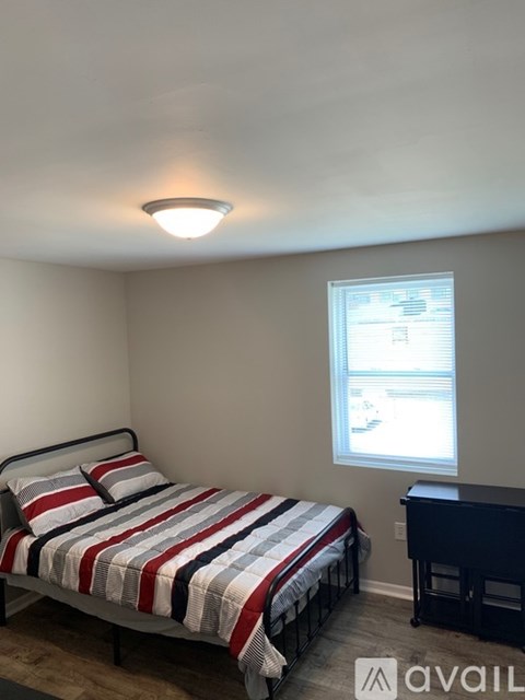 A bedroom with a bed, a dresser, and a window.